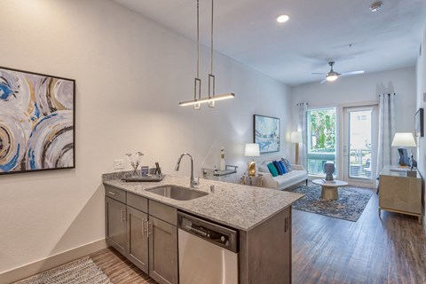 an open living room with a kitchen counter top and a sink