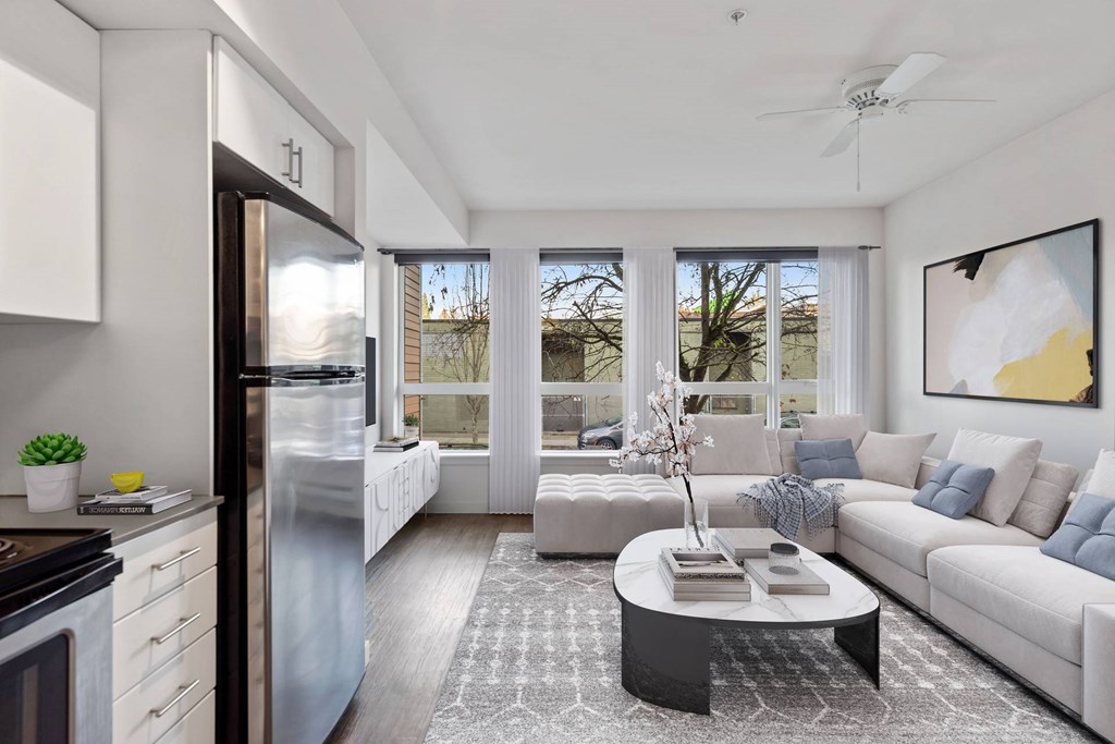 A modern kitchen with a refrigerator, a stove, a dining table, and a couch.