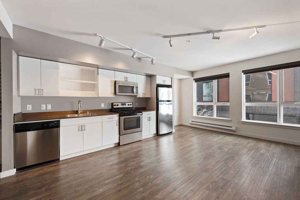 A modern kitchen with stainless steel appliances and wooden floors.