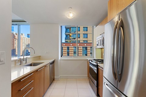 A kitchen with a stainless steel refrigerator and wooden cabinets.