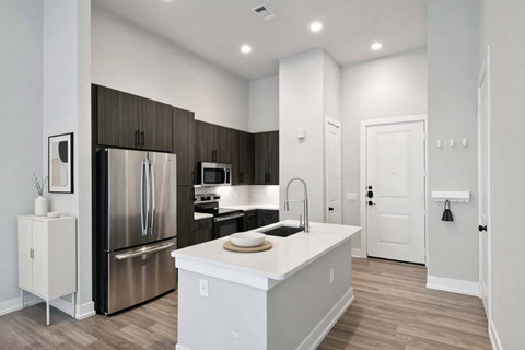 A modern kitchen with a stainless steel refrigerator and a white island.