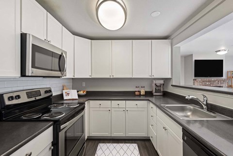 A kitchen with white cabinets and black countertops.