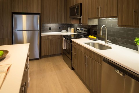A modern kitchen with a stainless steel refrigerator and a black microwave.