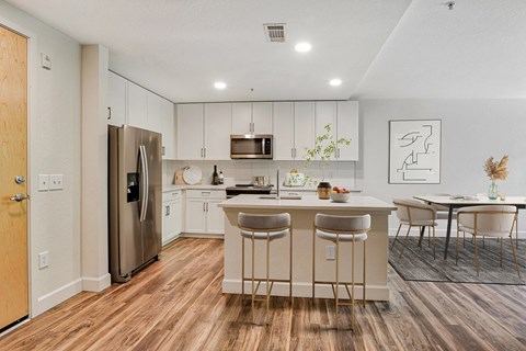 an open kitchen and dining area with a stainless steel refrigerator