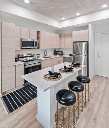 Kitchen with wooden cabinets and a white island with four black stools at Windsor Ludlam Trail in Miami, FL.