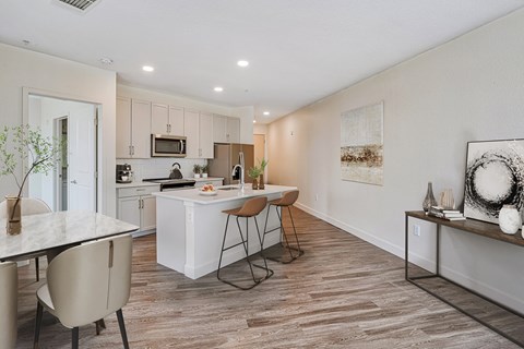 an open kitchen and living room with a dining area and a kitchen island with chairs