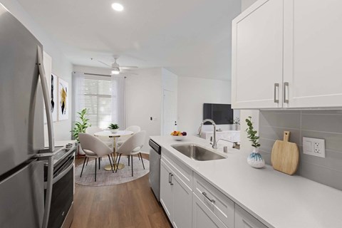 A modern kitchen with white cabinets and a wooden cutting board on the counter.