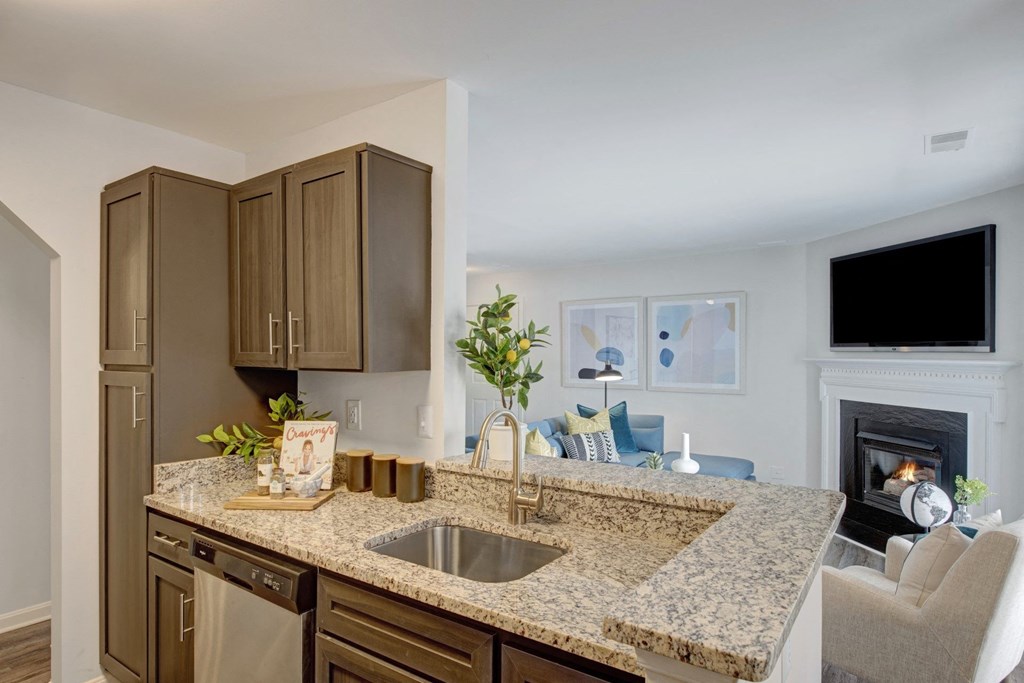 Kitchen with granite countertops and nearby living room with fireplace at Windsor Kingstowne, Virginia 22315