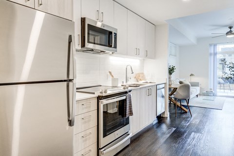 a kitchen with white cabinets and stainless steel appliances and a refrigerator