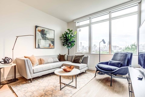 A living room with a grey couch, a blue chair, and a painting on the wall.