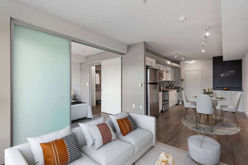 A modern living room with a white couch and a kitchen area in the background.