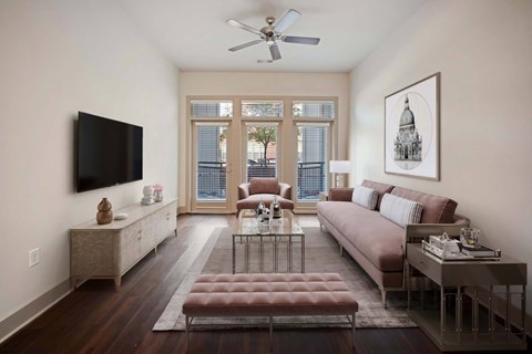 A living room with a brown couch and a television on the wall.