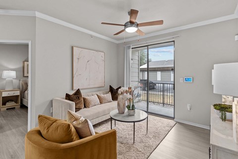 A living room with a brown armchair and a white couch with a brown pillow.
