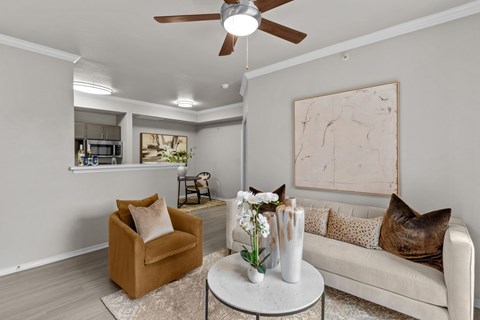A living room with a brown armchair, a white couch, and a round table with a vase of flowers on it.