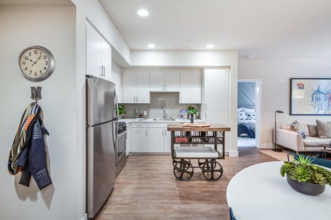 a kitchen with stainless steel appliances and a table with a rolling cart
