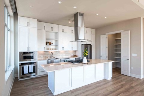 A kitchen with white cabinets and a large island at the Jordan by Windsor, Dallas Texas