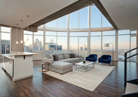 A modern living room with a kitchen area and a view of the city.