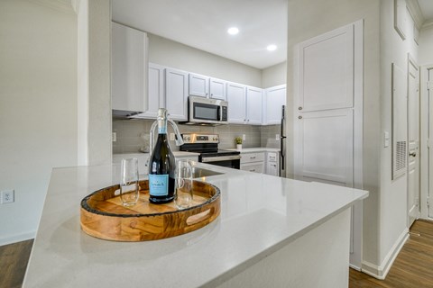 a white kitchen with a bottle of wine on a counter