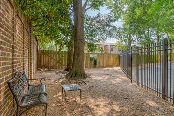 a courtyard with a bench and tree in front of a fence
