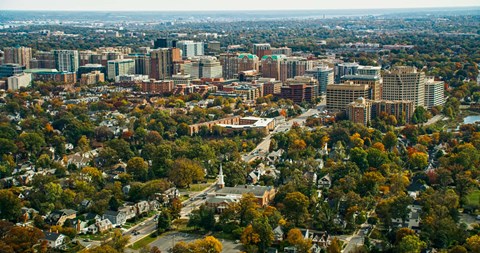 A cityscape with a mix of residential and commercial buildings surrounded by trees in autumn.