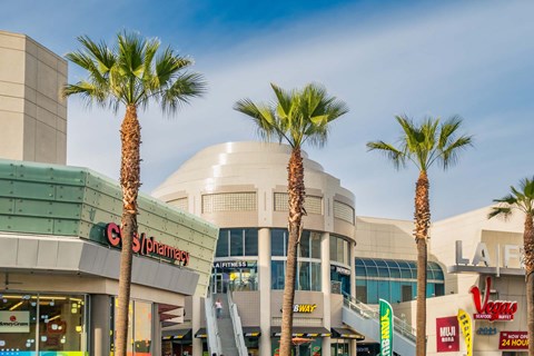 A shopping mall with palm trees and stores like Walmart and Best Buy.
