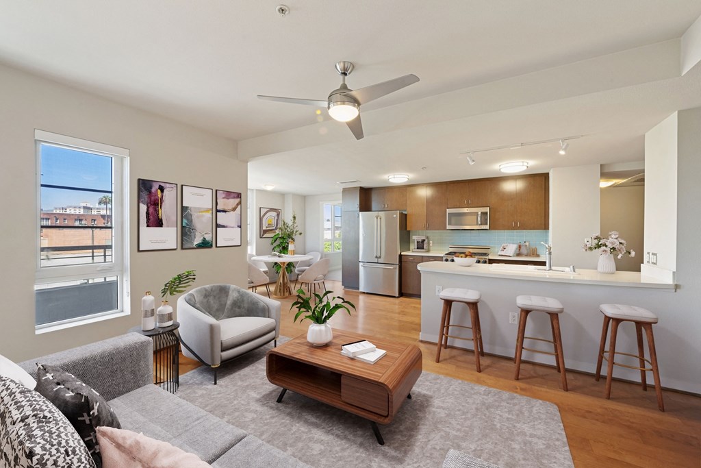 a living room with a couch and a coffee table and a kitchen with a bar