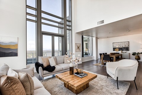 a living room with a couch and a coffee table and large windows