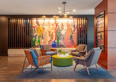 a living room with chairs and a large painting on the wall