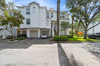 a large white apartment building with a car parked in front of it