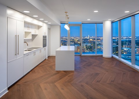 A kitchen with white cabinets and a wooden floor.
