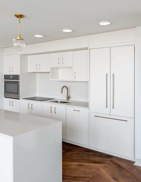 A modern kitchen with white cabinets and a wooden floor.