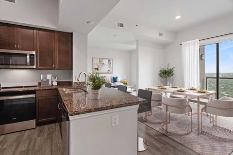A modern kitchen with a granite countertop and a dining area with a table set for four.