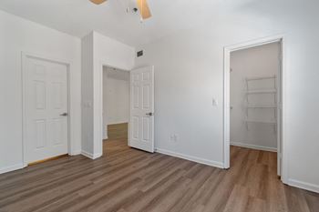 a bedroom with white walls and wood flooring and a closet
