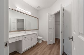 a bathroom with white cabinets and a mirror and a toilet