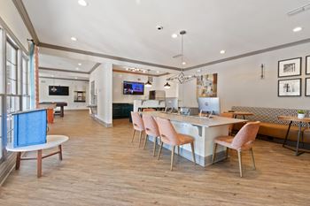 a communal area with a dining table and chairs and a kitchen with a large window