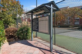 a sign in front of a tennis court with a fence