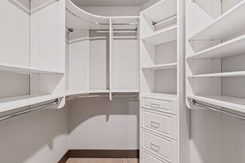 a walk in closet with white walls and white shelves and drawers