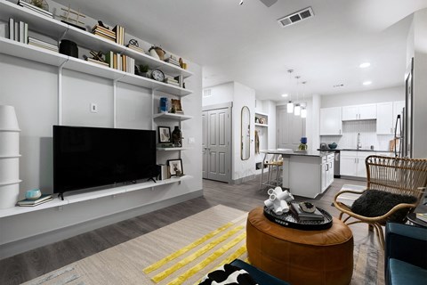 a living room with a tv and a kitchen in the background