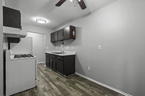 A kitchen with a white stove top oven and black cabinets.