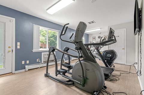 A home gym with a treadmill, elliptical trainer, and stationary bike.