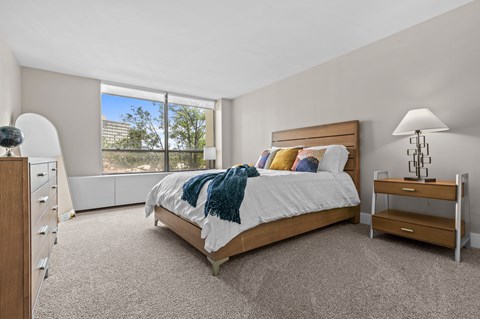 A bedroom with a large bed and a window overlooking a cityscape.