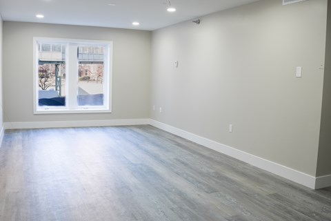 A spacious room with a large window and grey flooring.