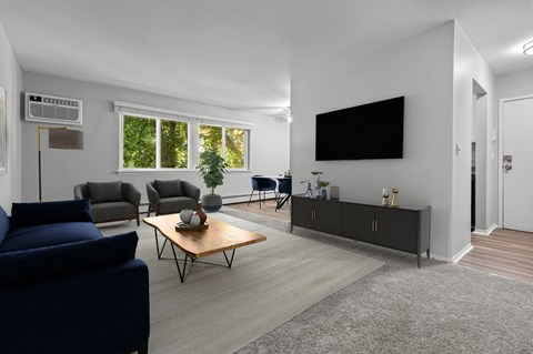 A living room with a blue couch, a wooden coffee table, and a flat screen TV mounted on the wall.