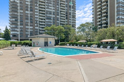 A swimming pool surrounded by lounge chairs in a residential area.