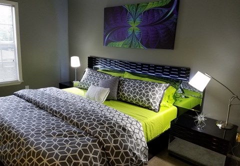 A bed with a black and white patterned comforter and a green pillowcase.