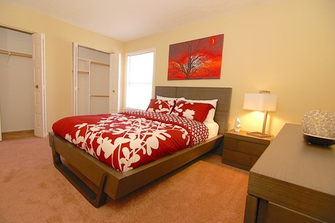 A bedroom with a large bed and a red and white comforter.