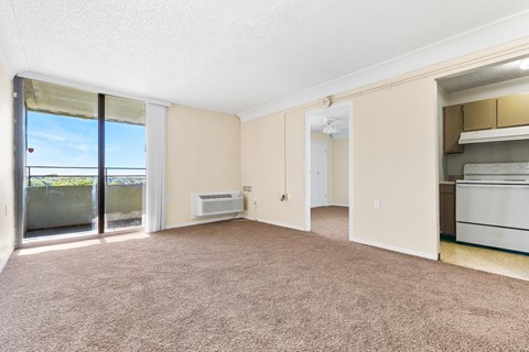A spacious living room with a sliding glass door leading to a balcony.