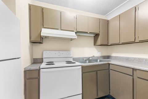 A white stove and sink in a kitchen with beige cabinets.