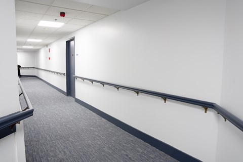 A long hallway with a blue carpet and white walls.