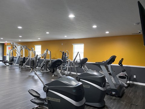 A gym with exercise equipment and a TV.